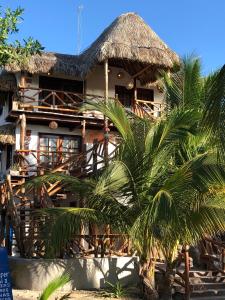 una casa con techo de paja y una palmera en Hotelito Crismi en Holbox Island