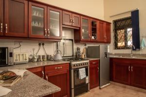 a kitchen with wooden cabinets and a stove top oven at Fred and Winnie BnB in Kampala