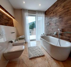 ein Badezimmer mit einer großen weißen Badewanne und einem WC in der Unterkunft Nobless Apartments Holedná Brno in Brünn