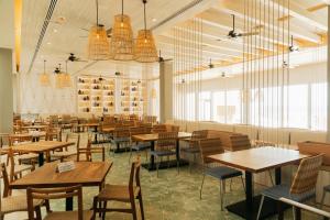 a restaurant with wooden tables and chairs and windows at Emporio Cancun - Buy All Inclusive Option in Cancún