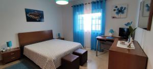 a bedroom with a bed and a desk and a television at Apartamento na Cidade do Surf in Peniche