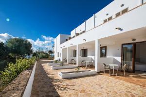 een wit huis met een rij stoelen en tafels bij Sol y Mar in Playa Migjorn