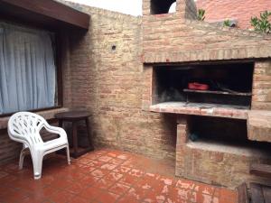 a white chair sitting in front of a brick fireplace at Complejo Casa Clara in Santa Clara del Mar