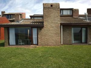 a brick house with a window and a lawn at Complejo Casa Clara in Santa Clara del Mar