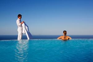 un hombre y una mujer en el agua con una tabla de surf en Carpe Diem Santorini, en Pirgos