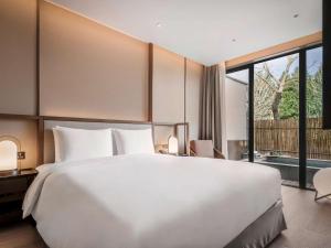 a bedroom with a large white bed and a large window at Ocean Spring Resort Chengdu - MGallery Collection in Chengdu +84 photos