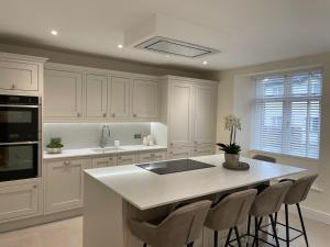 a kitchen with white cabinets and a kitchen island with stools at Edge Mere Apartment, Bowness-on-Windermere in Bowness-on-Windermere