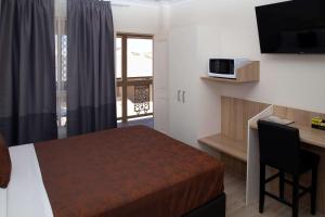 Habitación de hotel con cama, escritorio y TV. en Econo Lodge Park Lane, en Bundaberg