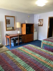 ein Hotelzimmer mit einem Schlafzimmer mit einem Bett und einem Schreibtisch in der Unterkunft Wigwam Motel in Cody