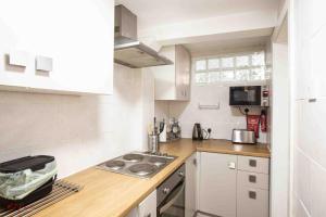 a small kitchen with white cabinets and a stove at Swannery Vista 1 Bedroom Apartment in Weymouth