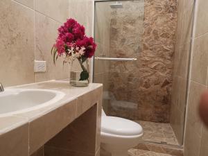 a bathroom with a toilet and a sink with a vase of flowers at El Zumbito in Valle de Anton +36 photos