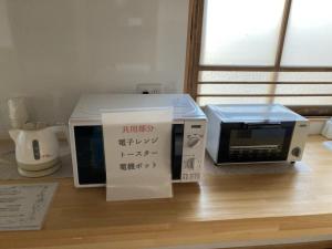 eine Mikrowelle und ein Toaster auf dem Tisch in der Unterkunft 沼津ライダーハウスしんちゃん in Numazu
