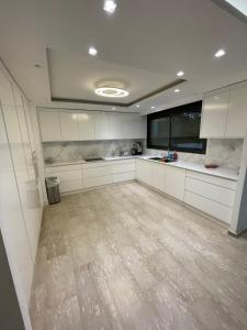 a large kitchen with white cabinets and a wooden floor at Villa white-design in Eilat
