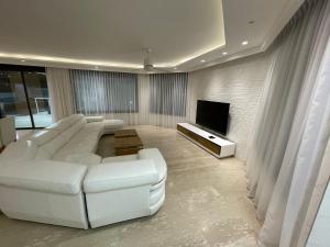 a living room with a white couch and a television at Villa white-design in Eilat
