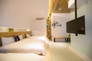 ein Hotelzimmer mit 2 Betten und einem Flachbild-TV in der Unterkunft 澎湖遛一遛旅店 in Magong