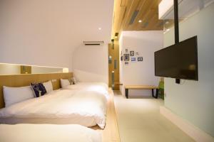 a hotel room with two beds and a flat screen tv at 澎湖遛一遛旅店 in Magong