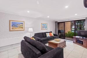 a living room with two couches and a flat screen tv at Paradise at The Bay in Nelson Bay