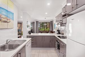 a kitchen with a sink and a refrigerator at Paradise at The Bay in Nelson Bay