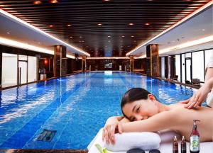 a man laying on a towel in a swimming pool at Guangzhou ChangFeng Gloria Plaza Hotel in Zengcheng