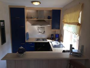 uma cozinha com armários azuis e uma bancada em Ferienhäuser im Sylter Gartenweg em Tinnum