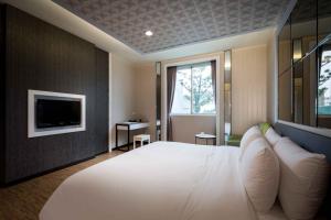 a bedroom with a large white bed and a tv at Alegran Motel in Wuqi