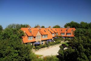 ein großes Haus mit Orangendächern und Bäumen in der Unterkunft Ferienhäuser im Sylter Gartenweg in Tinnum