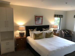 a bedroom with a large white bed with two lamps at Baycrest Thermal Lodge in Taupo