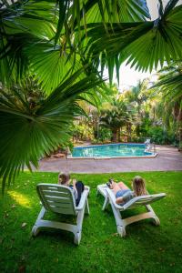 duas pessoas sentadas em cadeiras de jardim perto de uma piscina em Highway 1 Holiday & Lifestyle Park em Bolivar