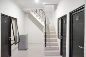 - un escalier dans une chambre blanche avec des portes noires dans l'établissement DPARAGON PAMELA 4, à Yogyakarta