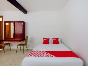 a bedroom with a bed with red pillows and a desk at OYO Hotel Emperador, Oaxaca in Oaxaca City