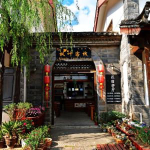 uma entrada para um restaurante com flores e plantas em Maple Leaf Inn em Lijiang