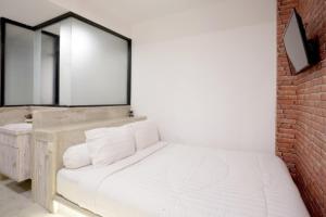 ジョグジャカルタにあるDPARAGON POGUNG Fの白いベッドとレンガの壁が備わるベッドルーム1室が備わります。