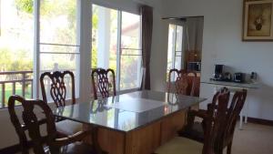 een eetkamer met een tafel, stoelen en ramen bij Peony Villa, 3 Bedroom Beachfront Pool Villa in Ko Chang