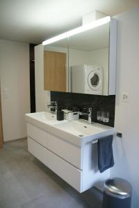 a bathroom with a white sink and a mirror at Haus Melchaazopf in Giswil