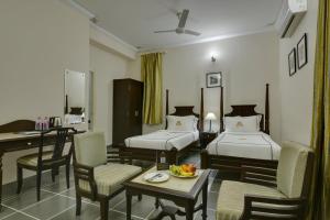 a hotel room with two beds and a table and chairs at Shahpura Dev Villa in Udaipur