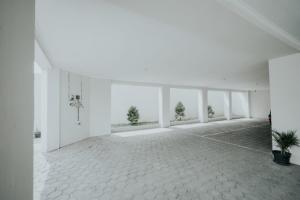 Habitación grande y vacía con paredes y ventanas blancas. en DPARAGON MT HARYONO en Semarang