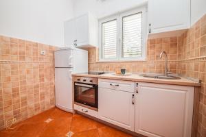 La cuisine est équipée d'un réfrigérateur blanc et d'un évier. dans l'établissement Apartments Batricevic, à Herceg-Novi