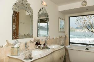 baño con 2 lavabos, bañera y ventana en Tintswalo Atlantic en Hout Bay