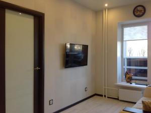 a living room with a television on the wall at Phan Thiet Apartments однокомнатные апартаменты с отдельной спальней in Velikiy Novgorod