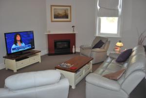 a living room with white furniture and a flat screen tv at Jacaranda Cottage in Murray Bridge