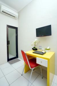 einen gelben Schreibtisch mit einem roten Stuhl in einem Zimmer in der Unterkunft DPARAGON IJEN NIRWANA in Malang