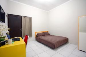 1 dormitorio con cama, mesa y escritorio amarillo en DPARAGON IJEN NIRWANA, en Malang