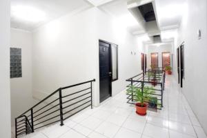 a hallway with stairs and a black door and a plant at DPARAGON DWIKORA in Palembang