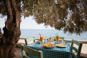 a table with food and drinks on a table under a tree at Giannis Seafront Studios in Korakas