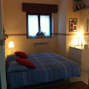 una camera da letto con un letto con cuscini rossi e una finestra di B&B Le Ortensie -Lago di Como a Lierna