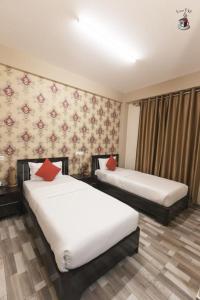a hotel room with two beds with red pillows at Newest Deluxe BnB, Ranee BNB in Shillong
