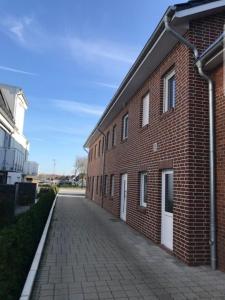 un edificio de ladrillo con puertas blancas y acera de ladrillo en Landhaus Braband Studios - Rugenbargsweg 17, en Cuxhaven