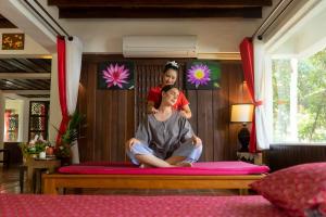 a man sitting on a bed in a room at Legendha Sukhothai Hotel - SHA certified in Sukhothai