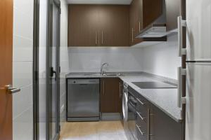 una pequeña cocina con fregadero y nevera. en Barcelona Apartment Gran de Gràcia, en Barcelona