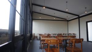 a dining room with tables and chairs and windows at DJURAGAN KAMAR SLIPI in Jakarta